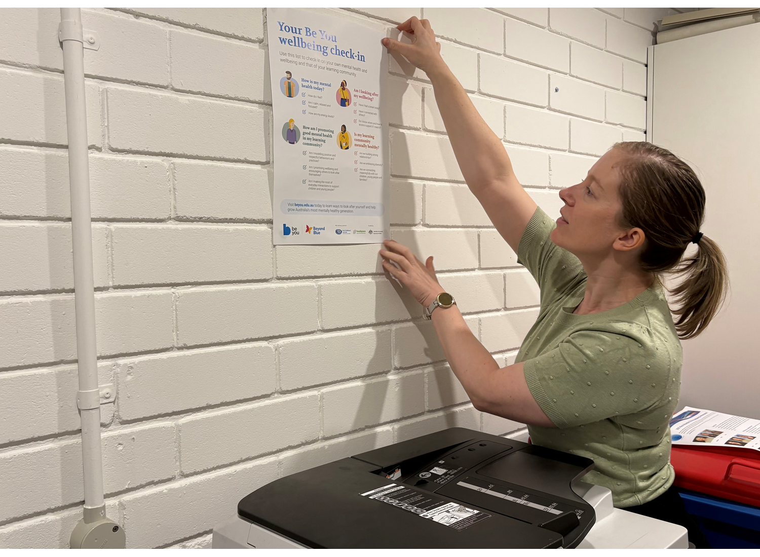 Dr Kayla Ball putting up a poster on a wall