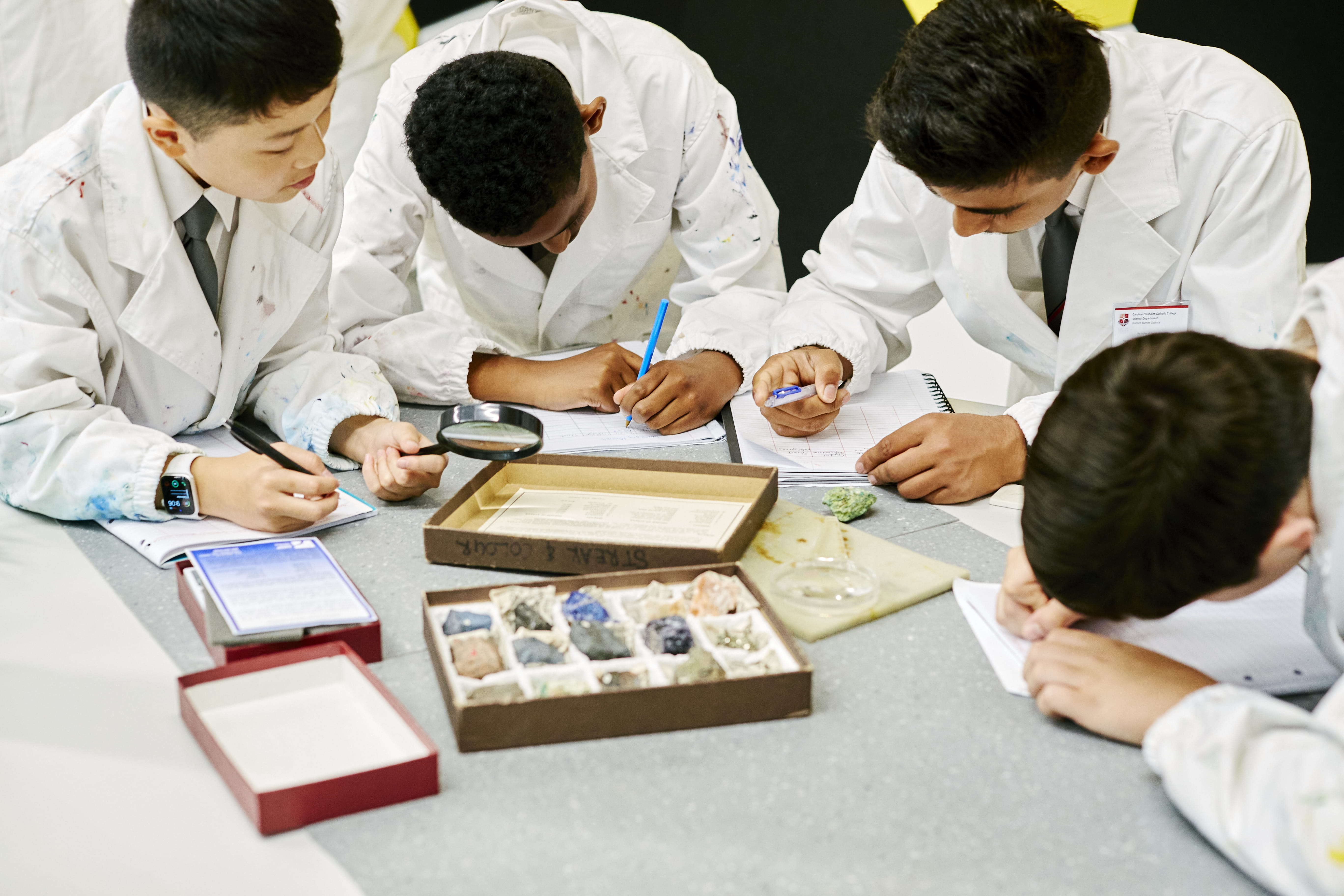 Four secondary students standing around a bench, doing a science experiment.