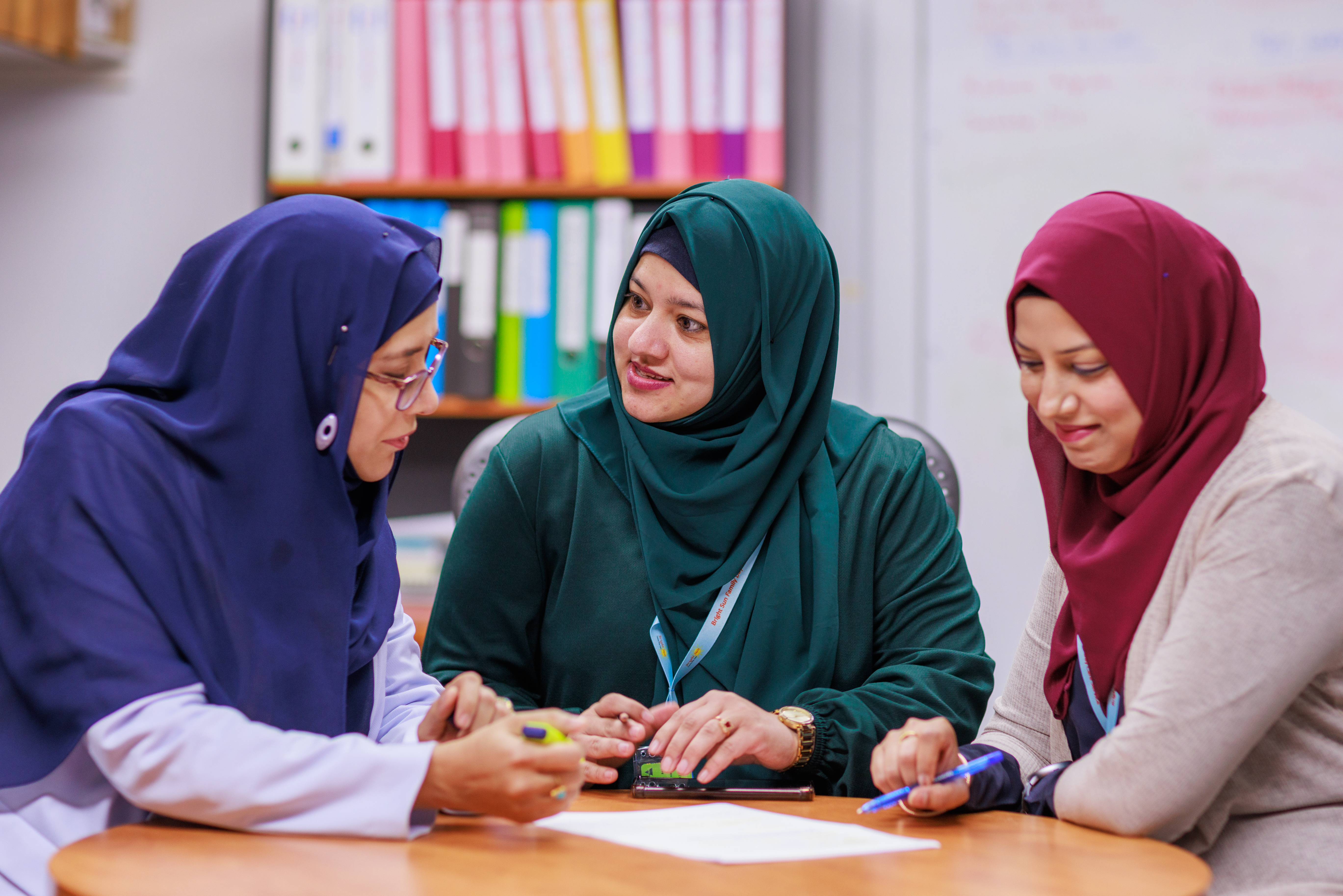 Three educators sitting around a table and talking to each other.