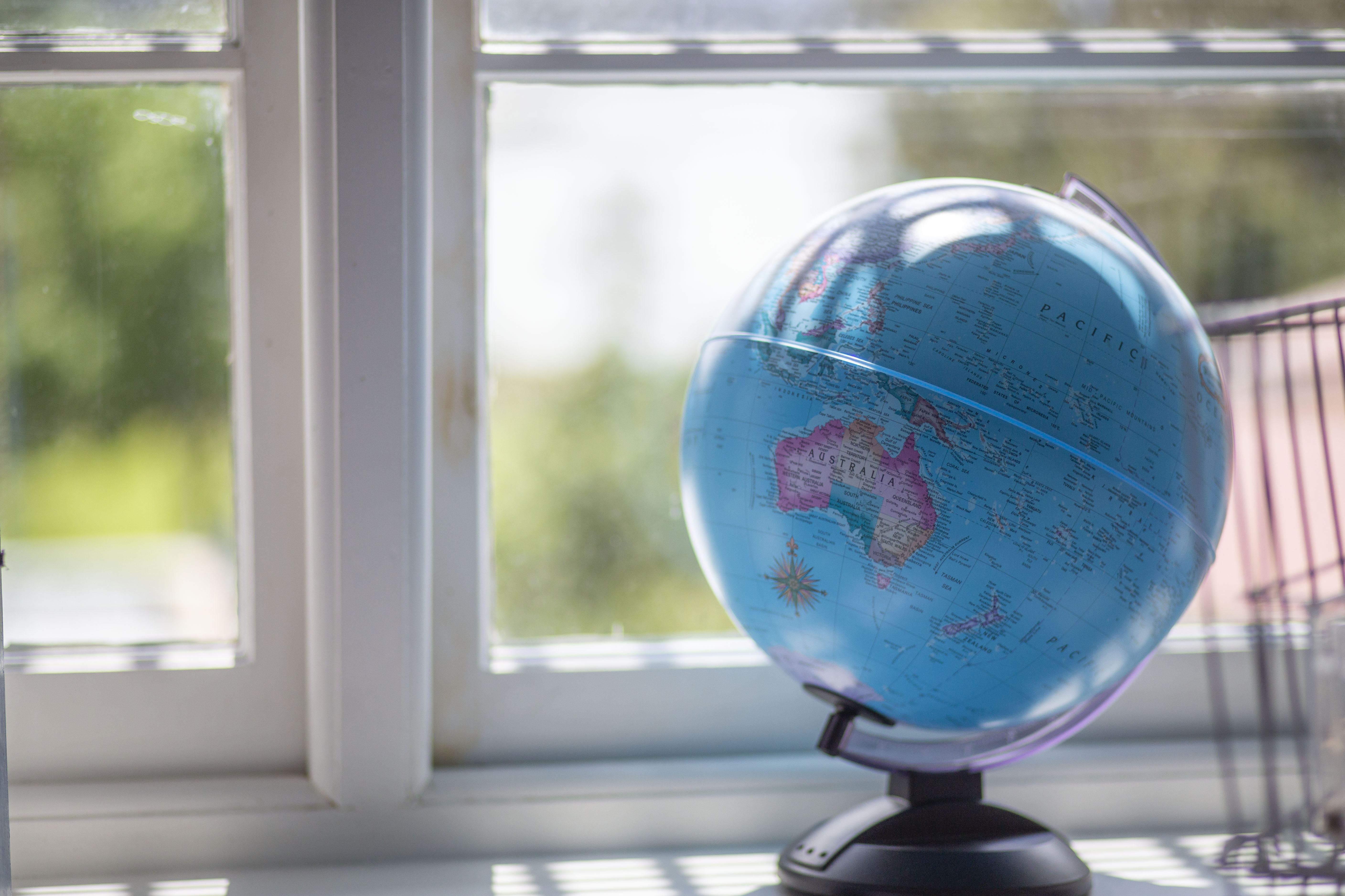 A globe of the world on a window sill.
