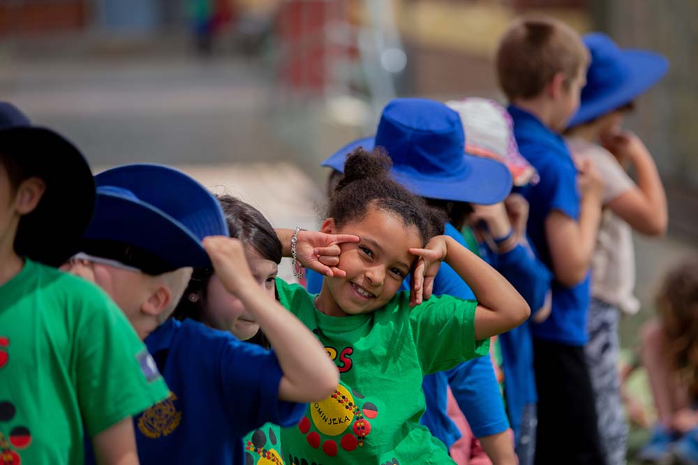 Young children in a line, smiling at the camera