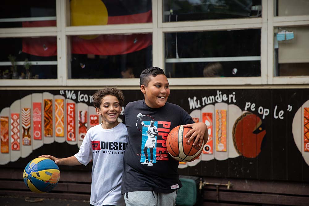 Two children holding basketballs, smiling