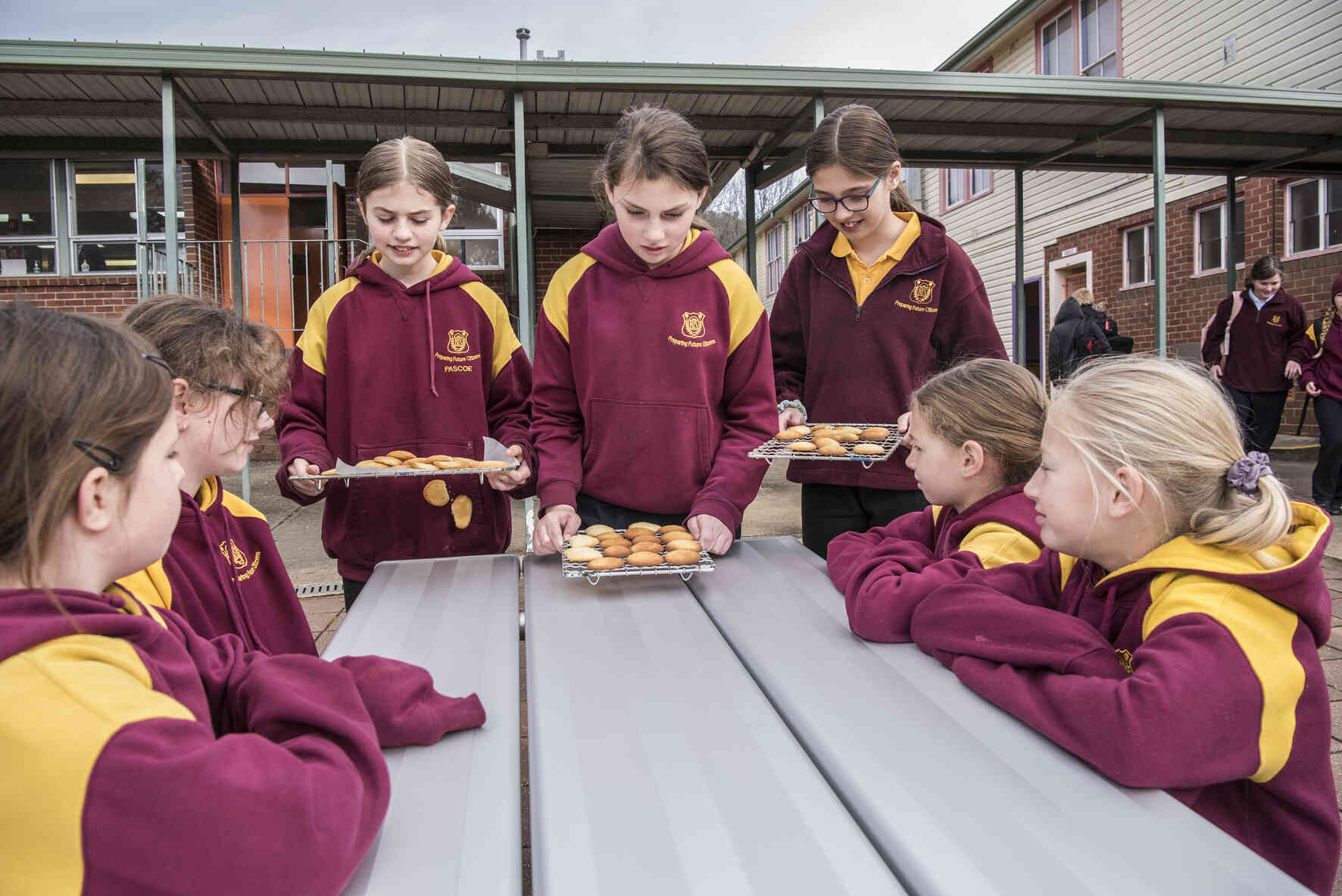 Children bringing trays of baked goods to a table of peers