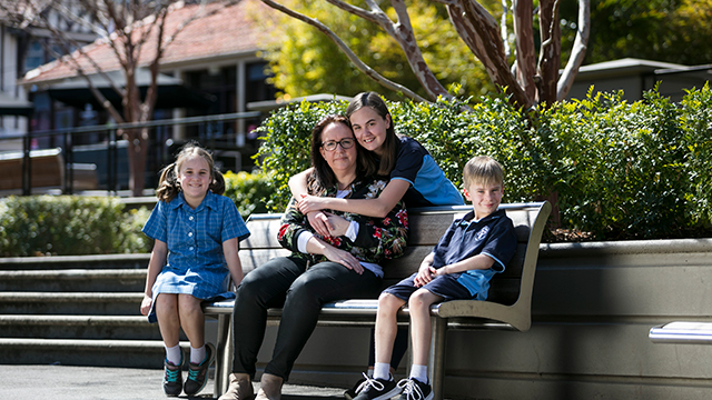 Three children and an adult, sitting on an outdoor bench