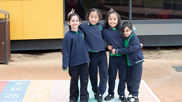 Four smiling children standing together in the schoolyard