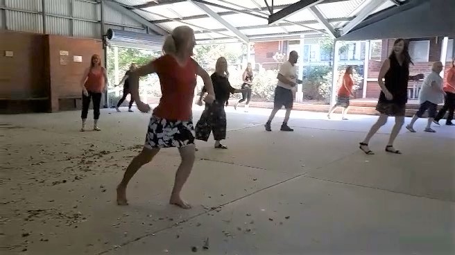 Teachers in a hall, partaking in a dance class