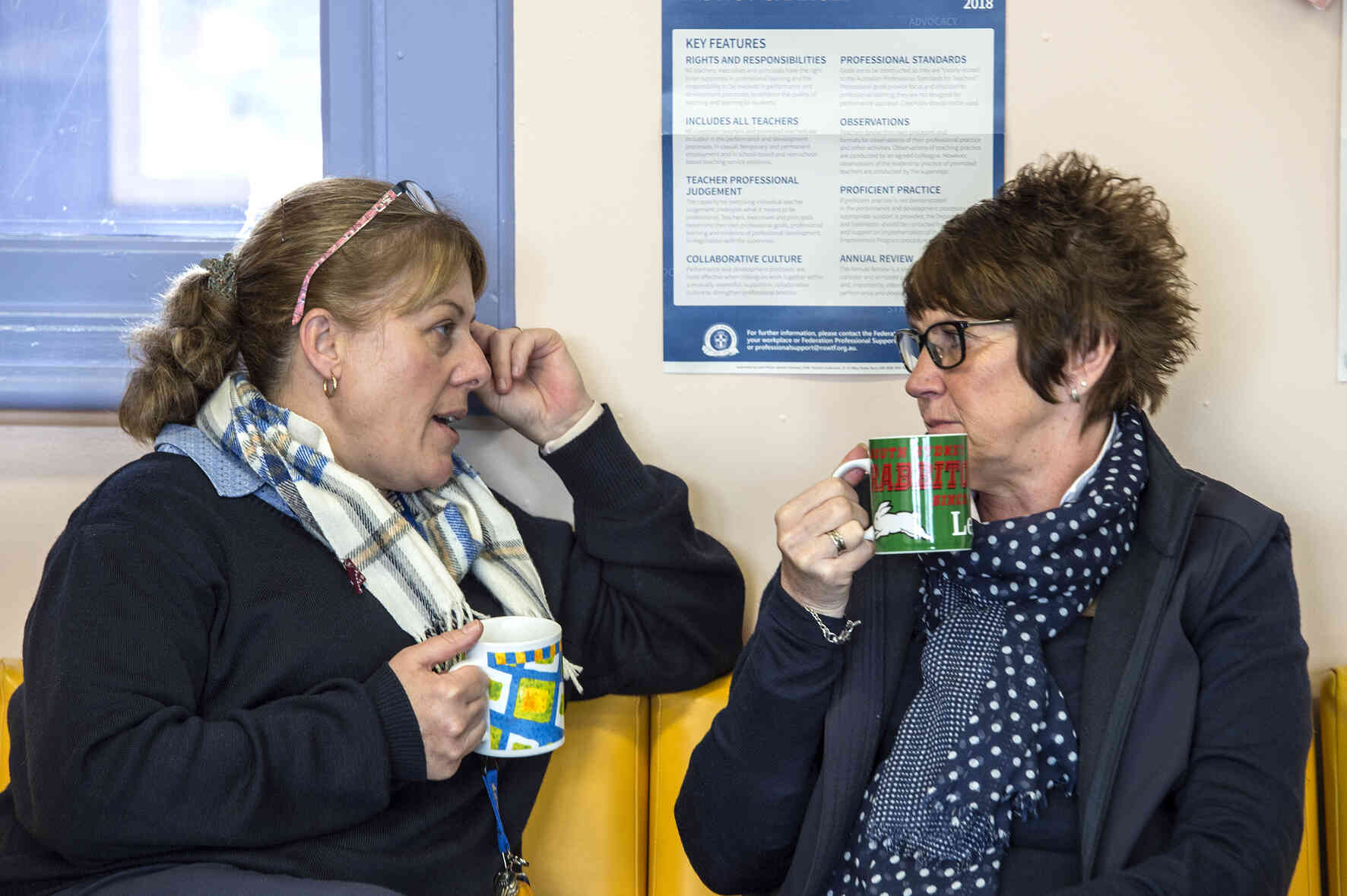 Two educators drinking tea, engaged in conversation