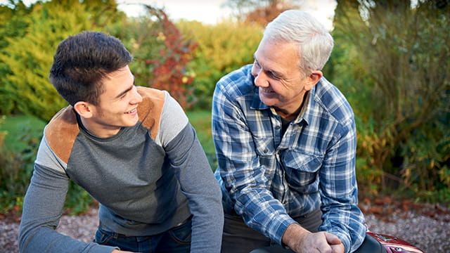 An adolescent and family member sitting together, smiling 