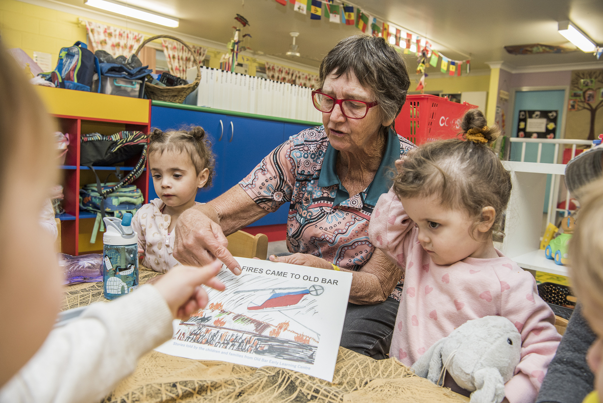 An adult and young children, looking at a drawing together