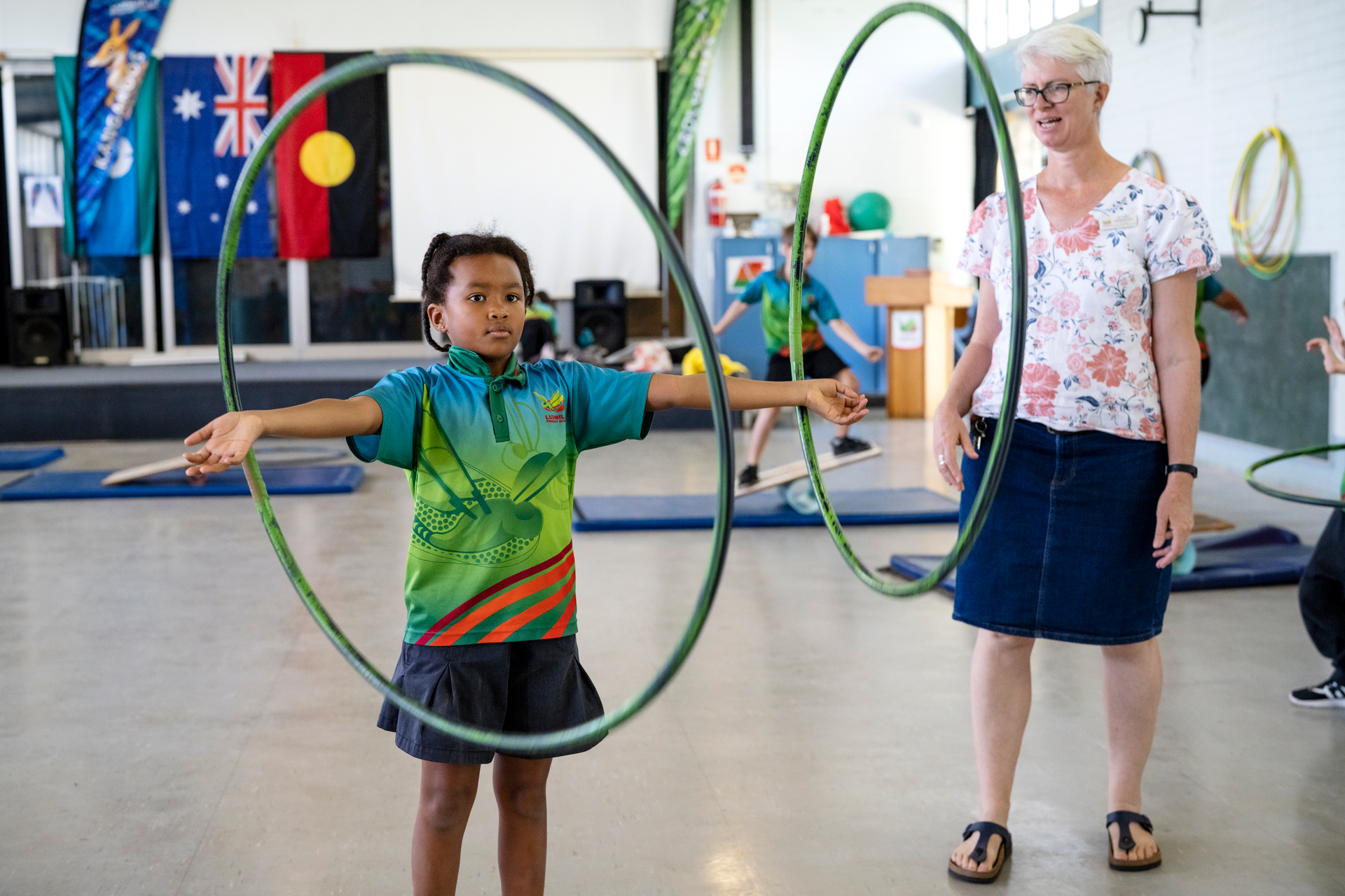 A child playing with hula-hoops, with an educator looking on 