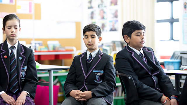 Young people in a classroom, practising mindfulness