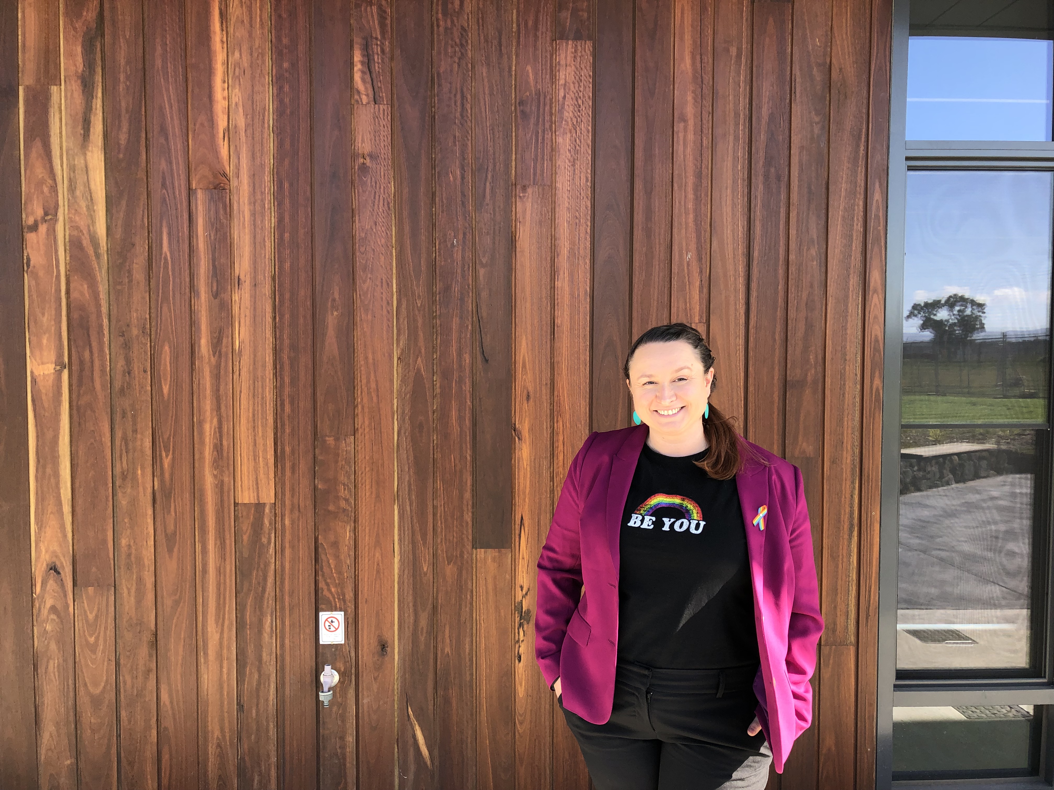 An educator smiles while standing outside