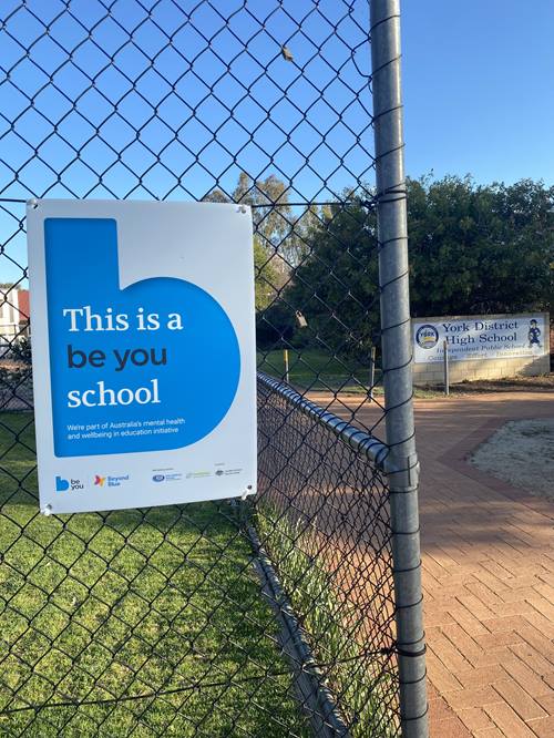 A Be You sign on a school fence that reads "This is a Be You school"