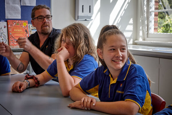 two children and an educator sitting at a desk