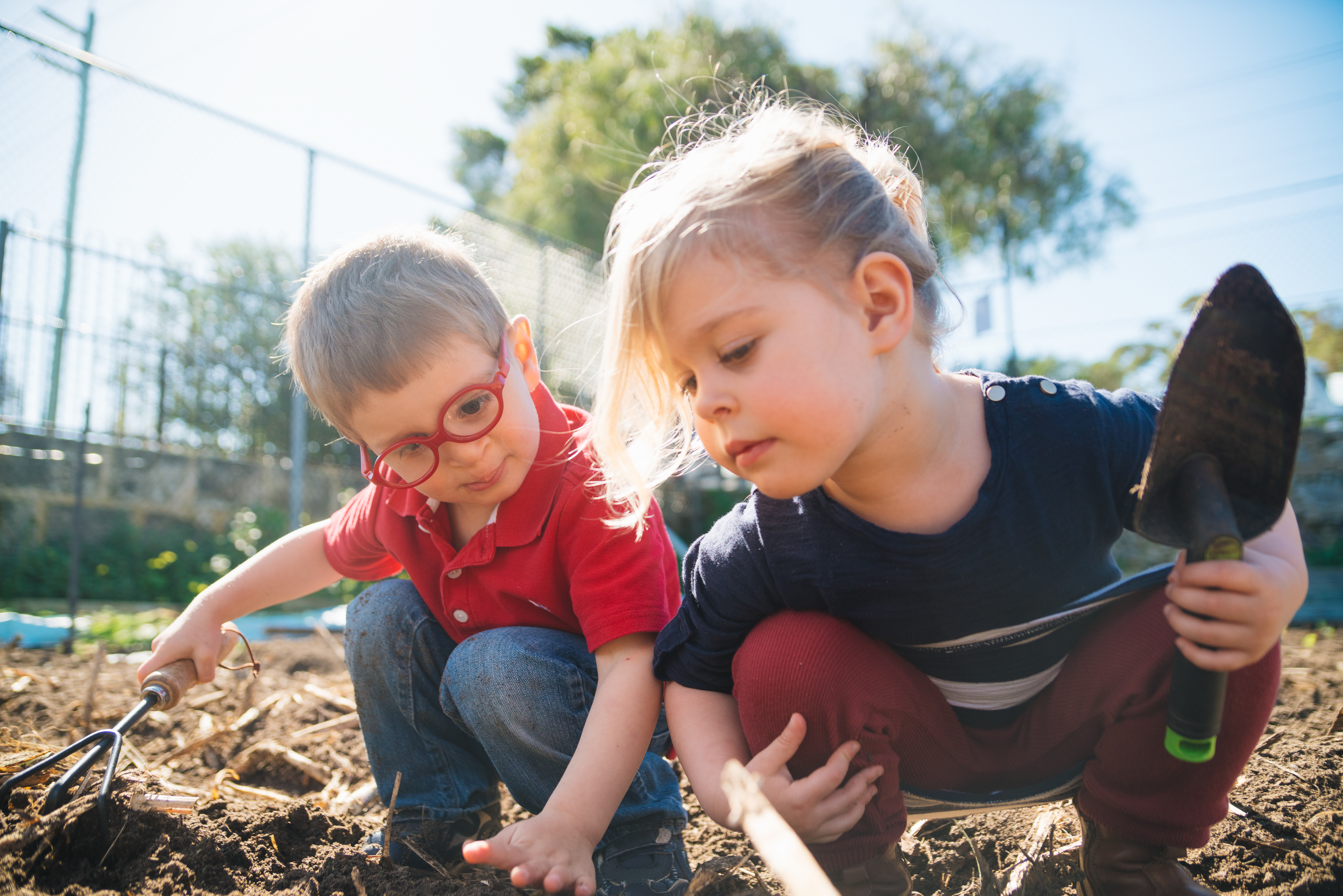 Two young children digging in a garden