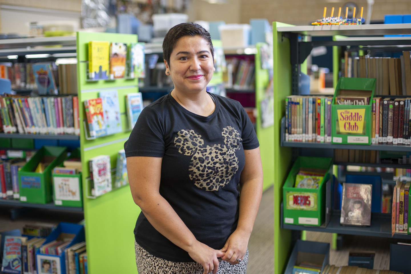 A special needs educator in a library, smiling at the camera 