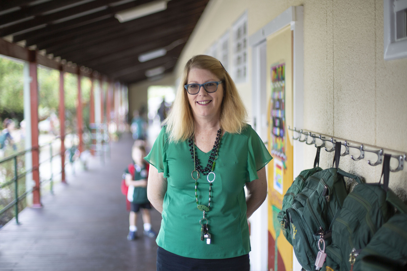An educator standing outside a school, smiling at the camera
