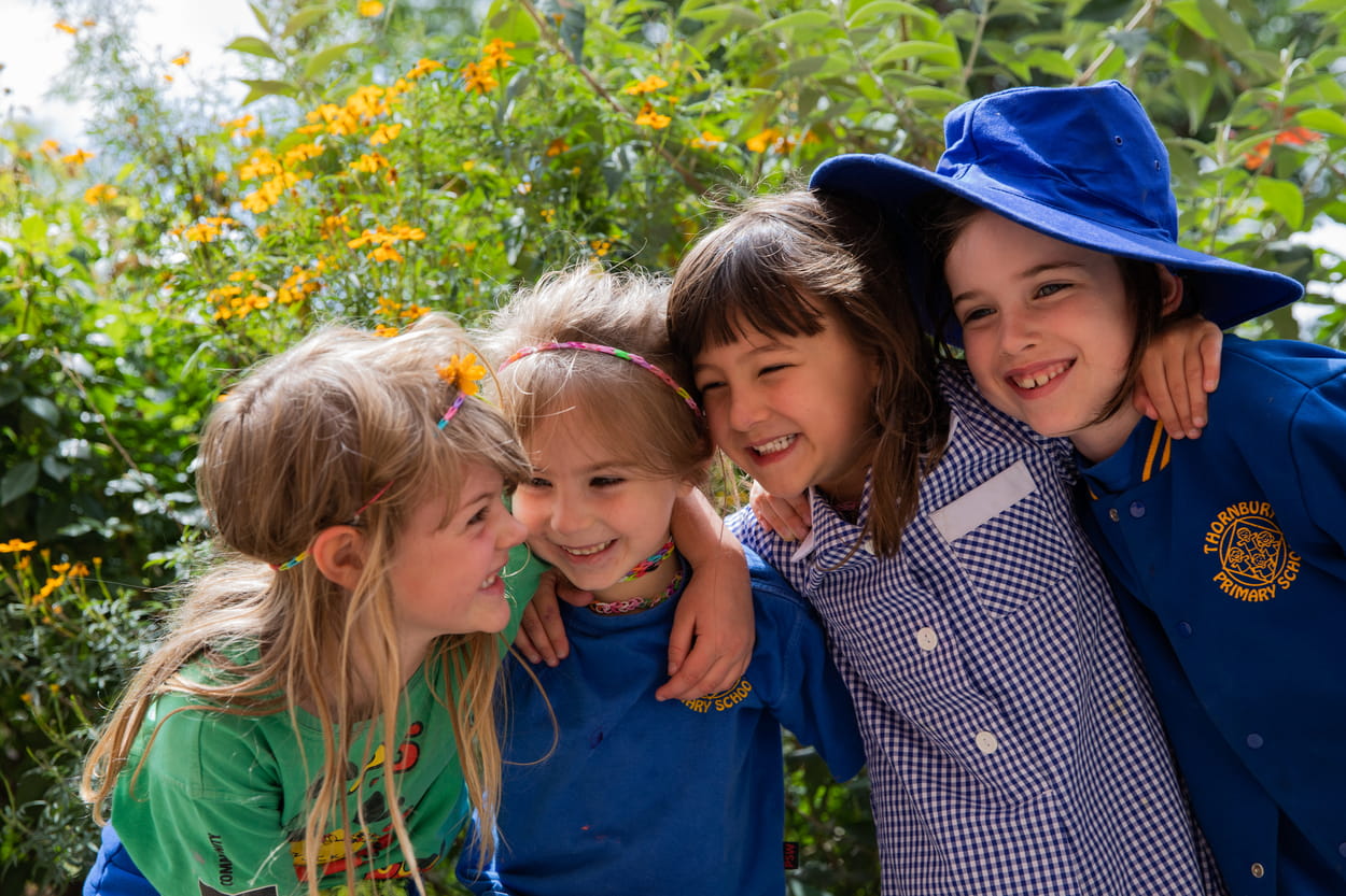 Four children standing with their arms around each other's shoulders