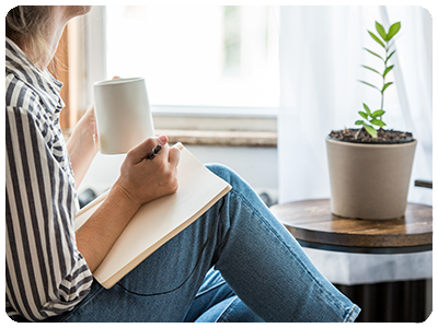 An adult journalling while drinking tea