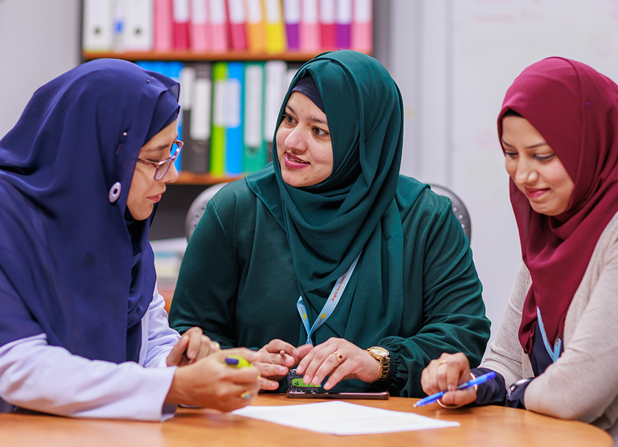 Photo of three educators having discussion around a table.