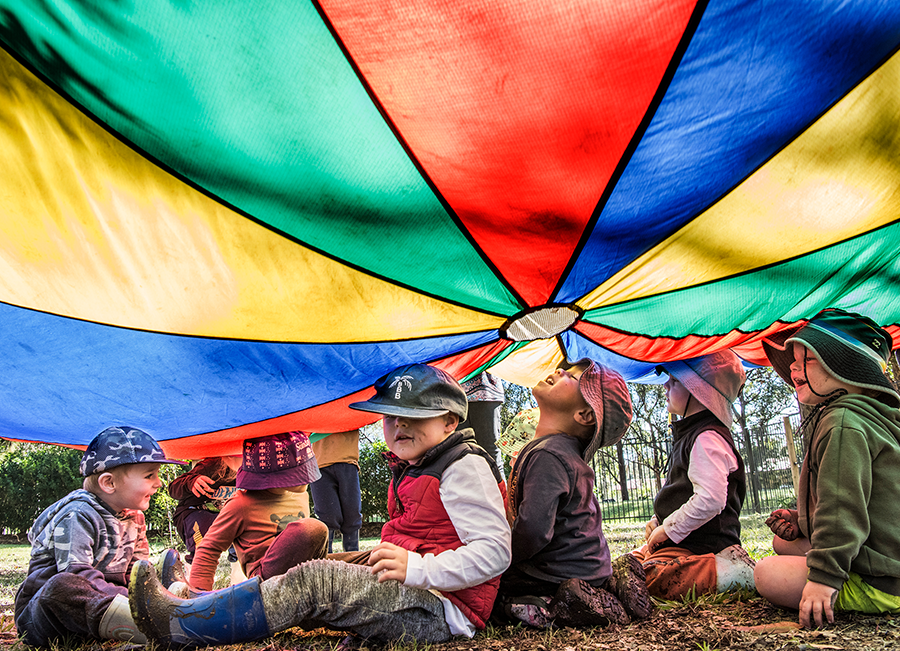 Photo of children playing under colourful parachute.