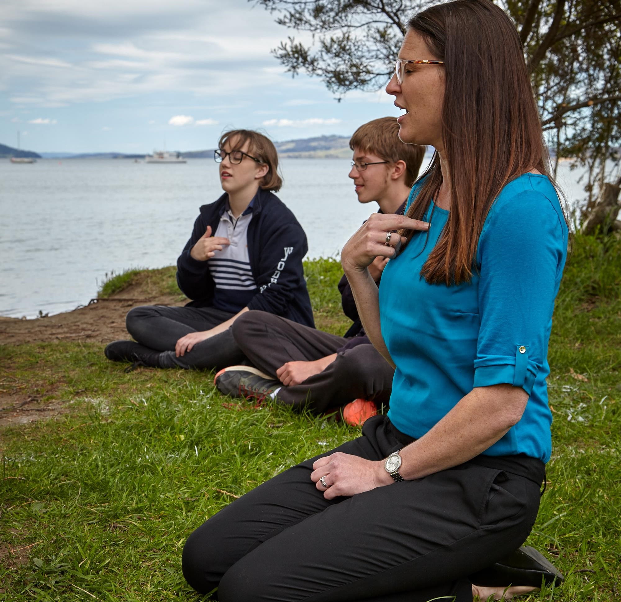 An educator and adolescents sitting in a circle, engaged in an activity