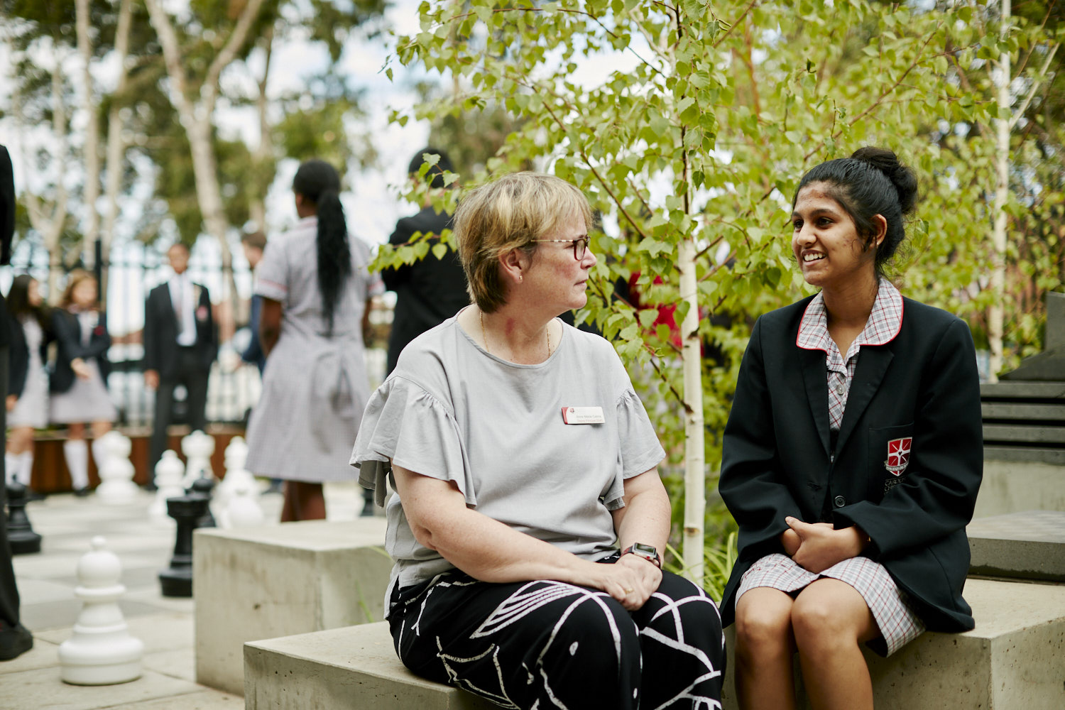 An educator sitting with an adolescent, engaged in conversation