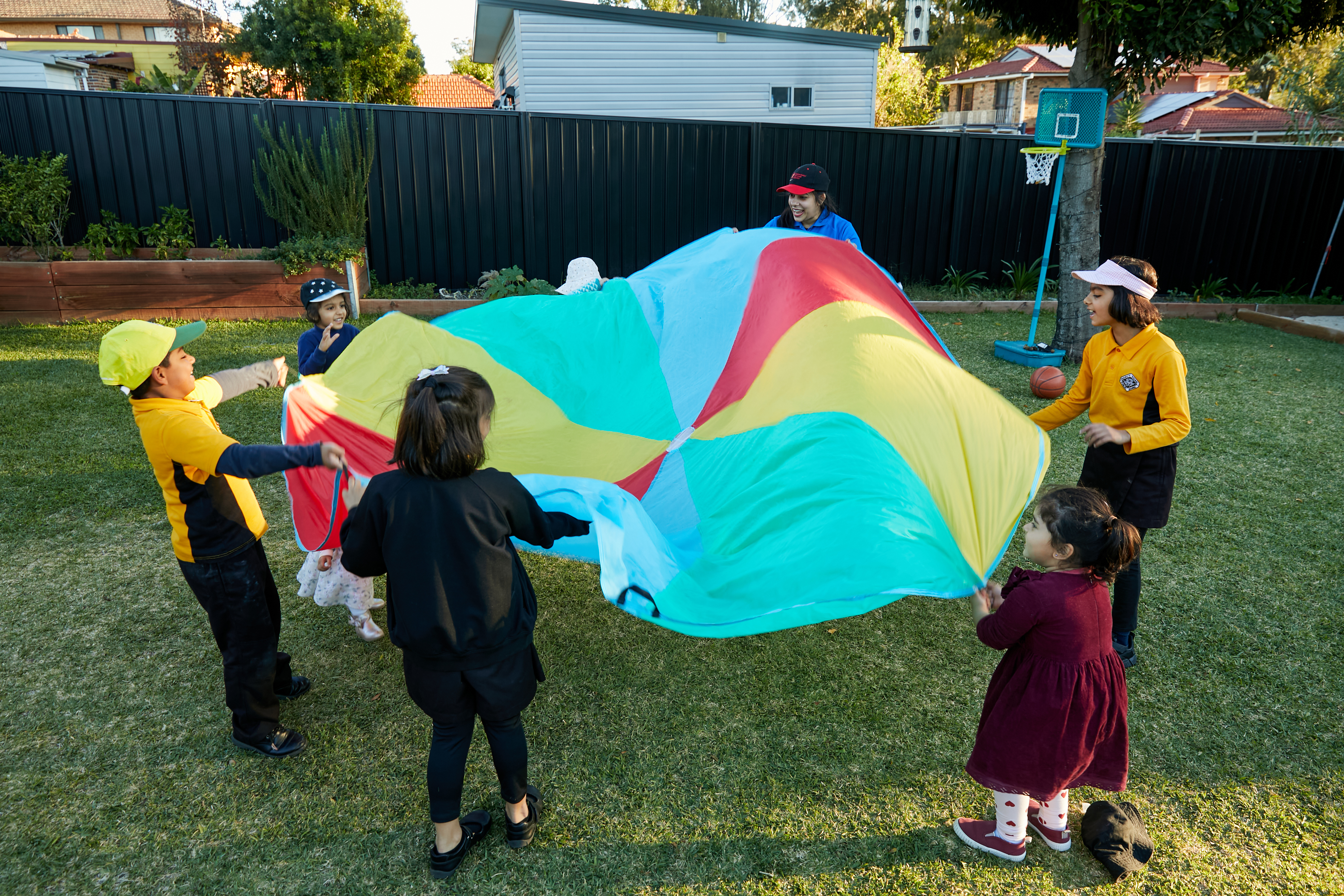 A group of children standing in a circle, holding a parachute as part of a game