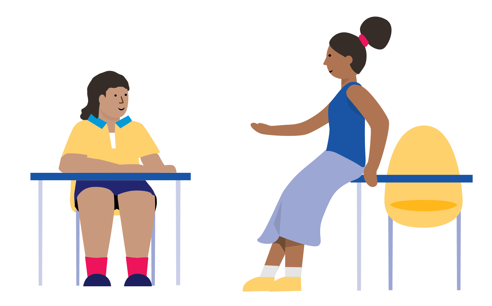 A student sitting at a desk talking to a teacher who is leaning against another desk