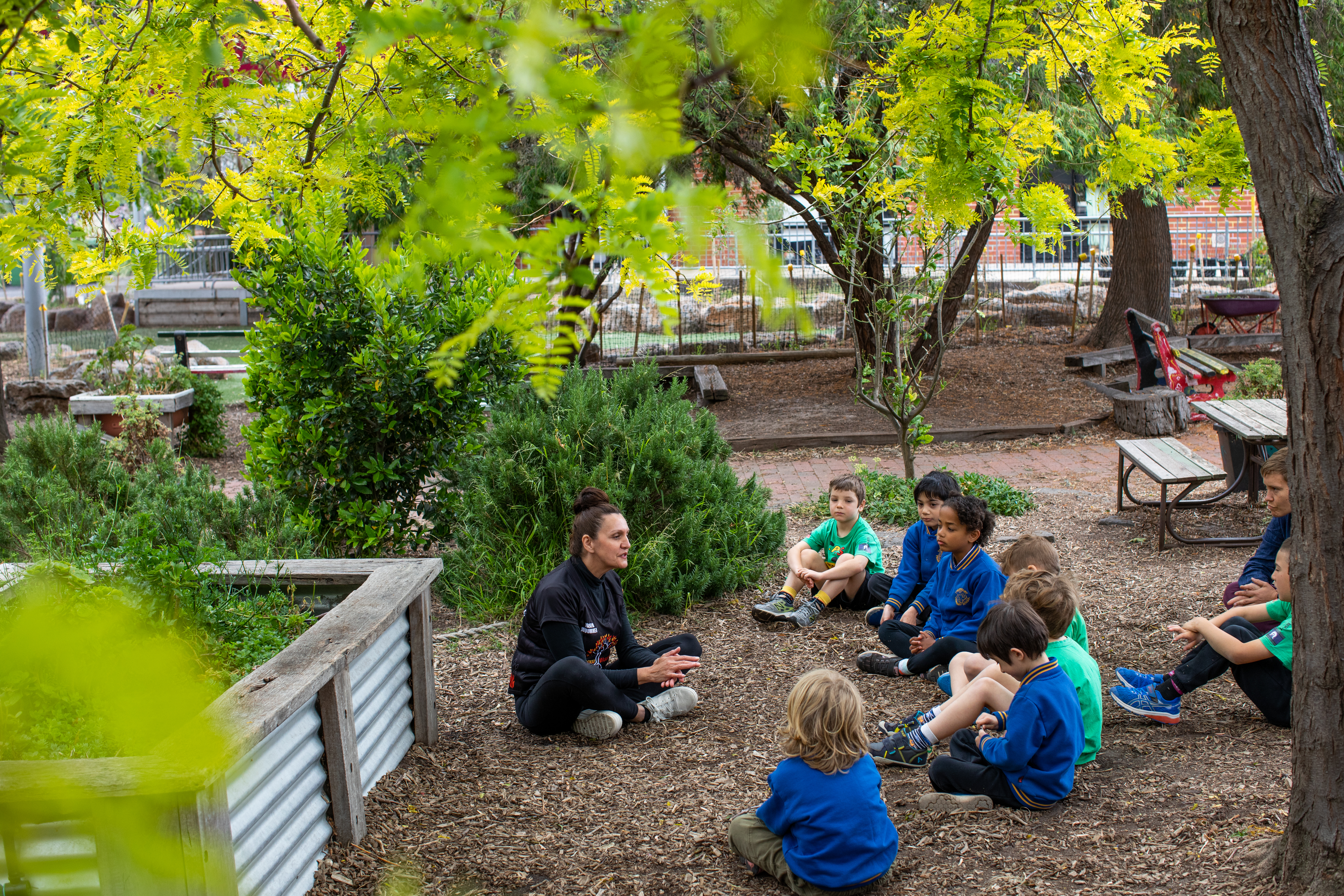 An educator sitting in a garden with young children