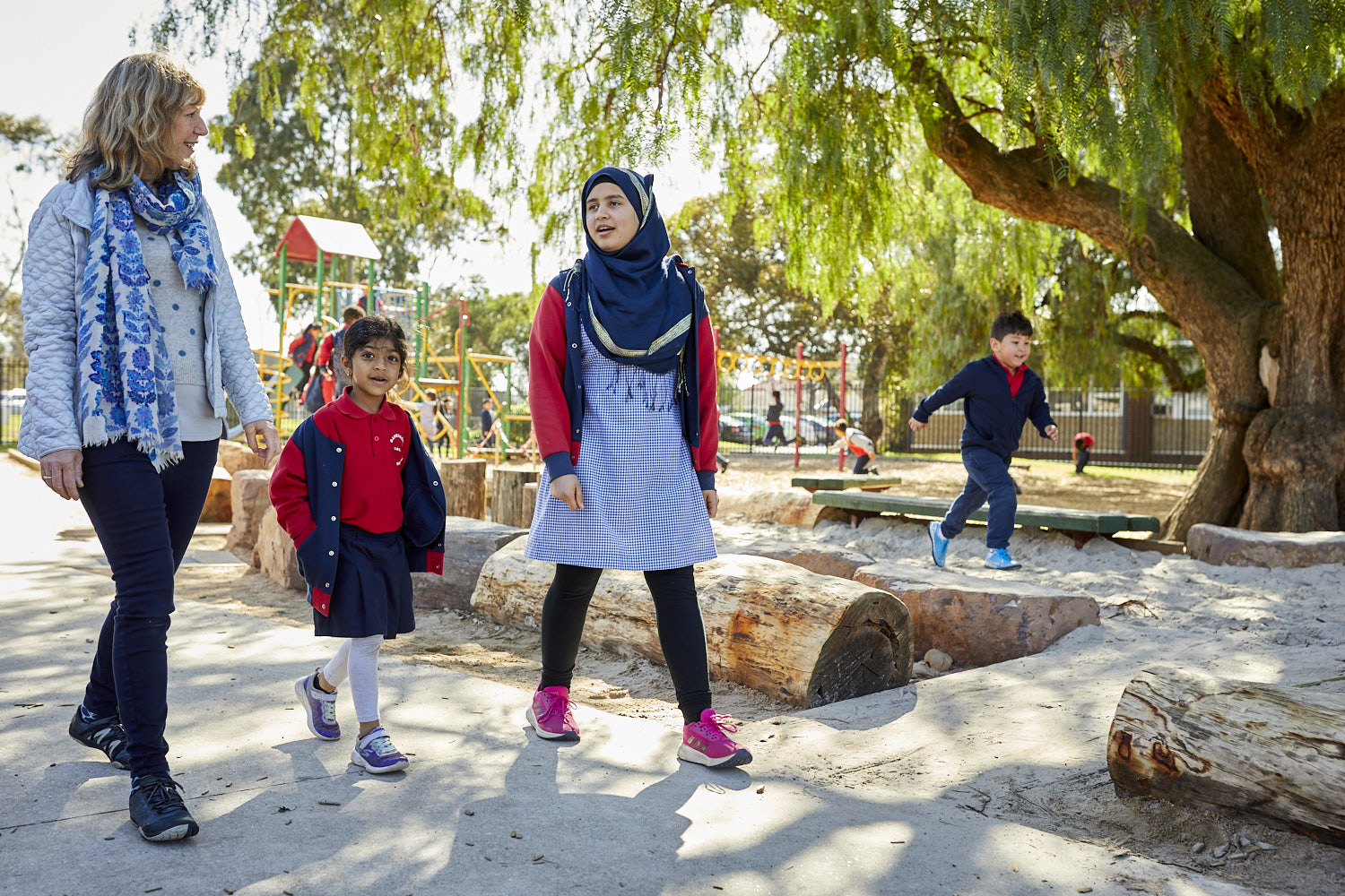 Two adults and a child, walking through a playground