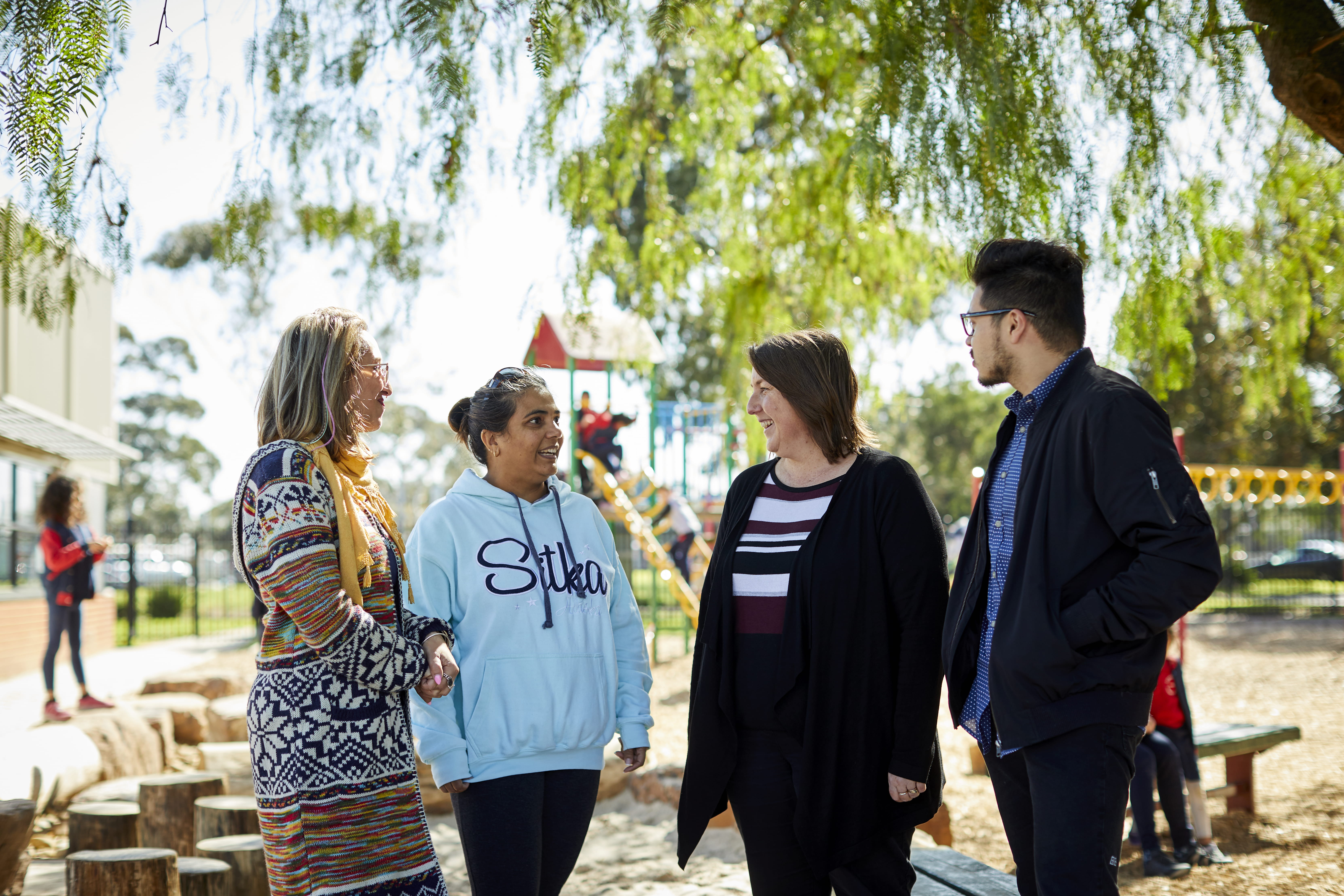 A group of adults standing outside, engaged in conversation