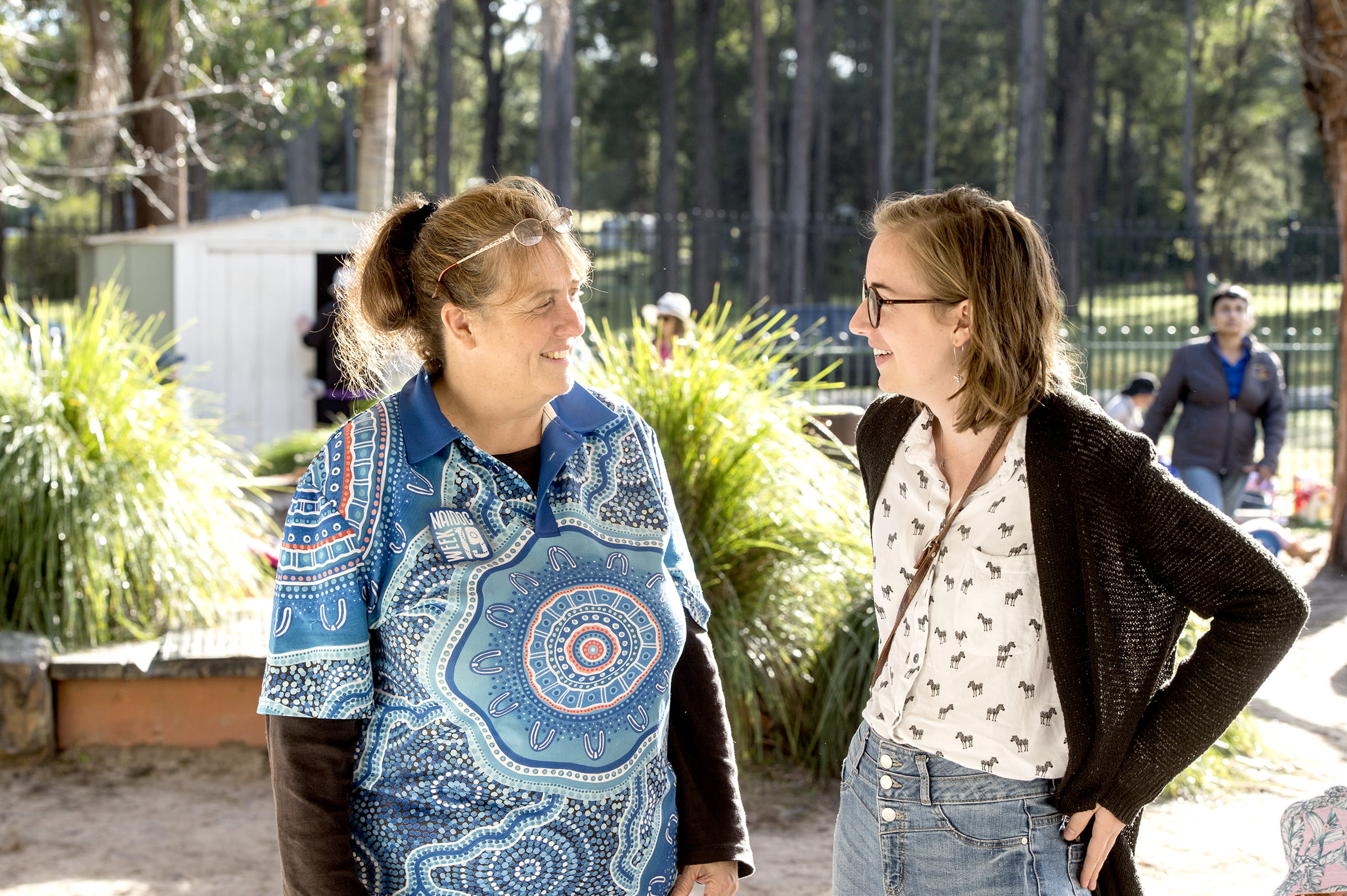 Two educators smiling and talking to each other outside