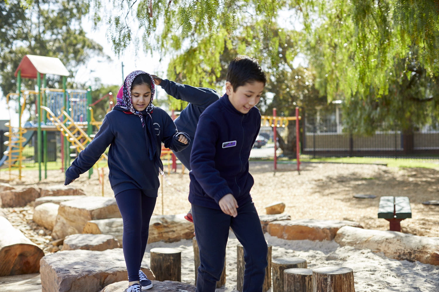 Two primary school aged children walking and balancing along steps of different heights. 