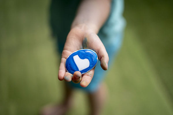 A young child holding a stone painted with the BeYou logo 