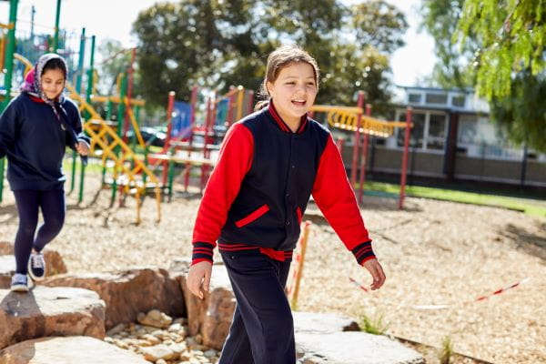 Two children walking in a playground, smiling