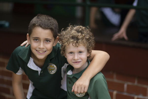 Two children with their arms around each other, smiling at the camera