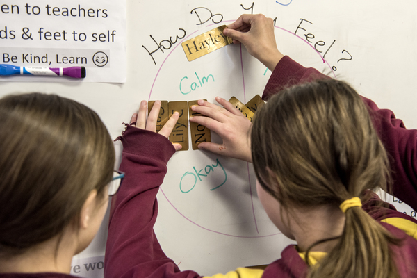 Children placing cards on a 'How do you feel?' chart