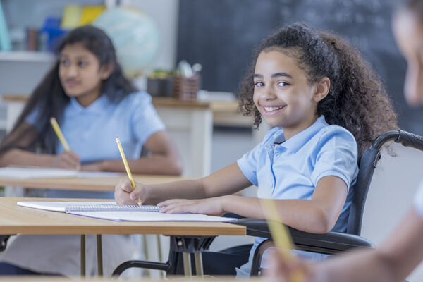 A young child working in a classroom, smiling at the camera