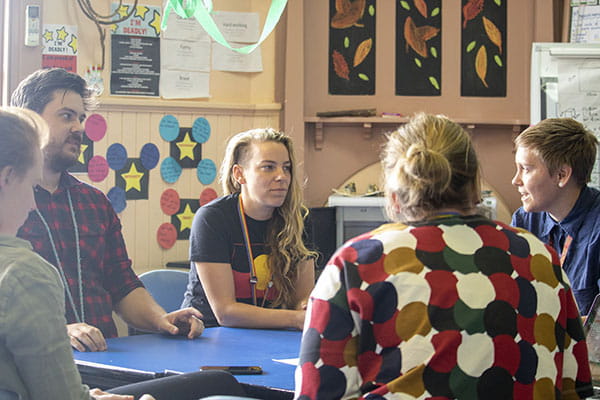 A group of educators sitting around a table, engaged in conversation