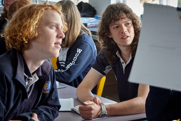 Two adolescents listening to the teacher