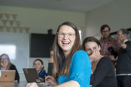 A woman smiling in a classroom with other people