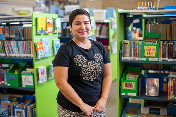 A special needs educator in a library, smiling at the camera