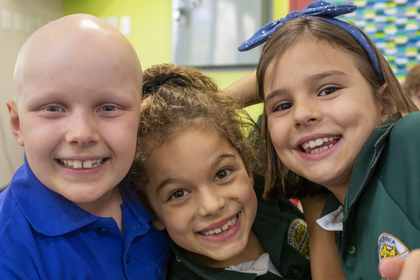 Three children with their arms around each other, smiling at the camera