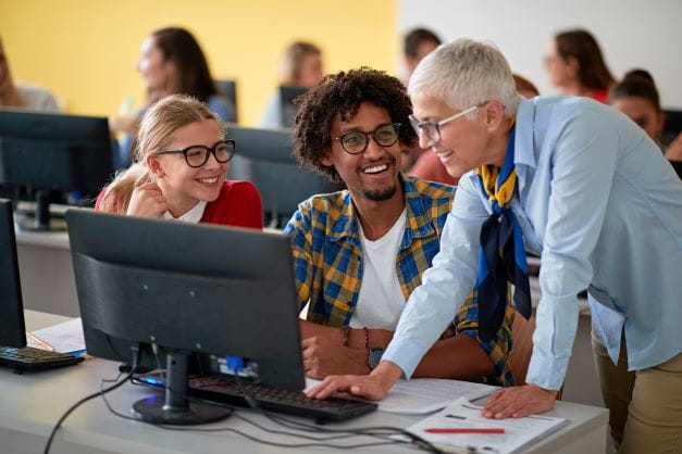 Three adults gathered around a computer