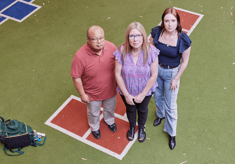 Educators standing in schoolyard looking up at the camera