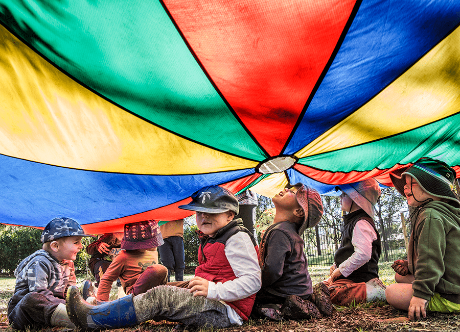 Photo of children playing under colourful parachute.